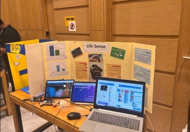Photo of the project poster, computer displaying the project's code, and a prototype.