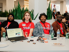 Students sit behind a table, demonstrating the Buddy Up System.