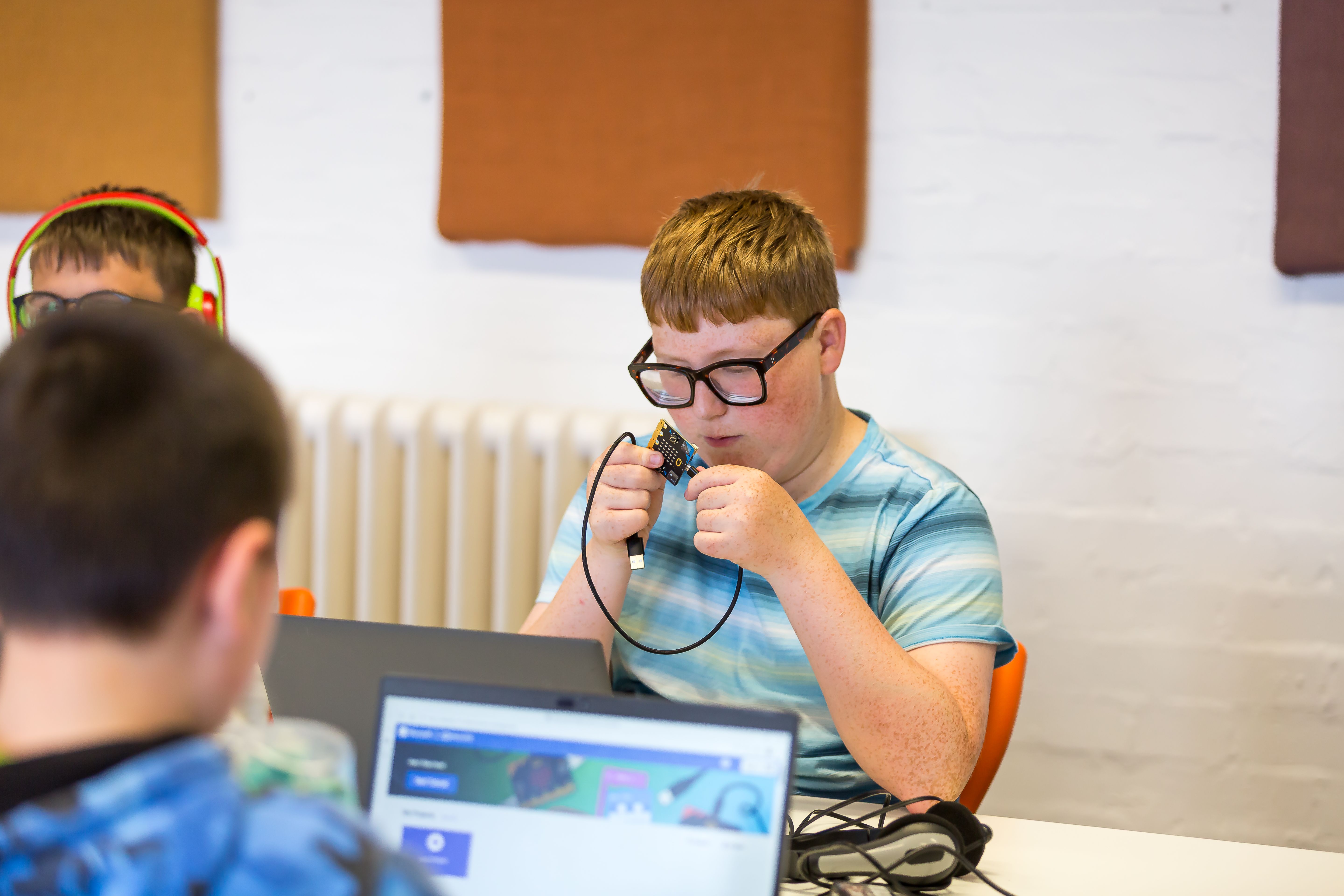 A student exploring a micro:bit with braille capital A and B labels above the buttons.