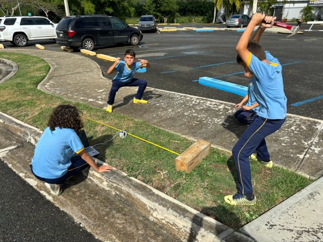3 children conduct an outdoor experiment using a micro:bit, tape measure, block of wood and a hammer
