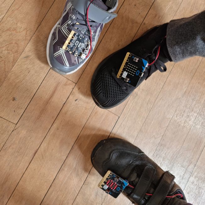 3 feet pose in a circle, with micro:bits attached to measure their steps