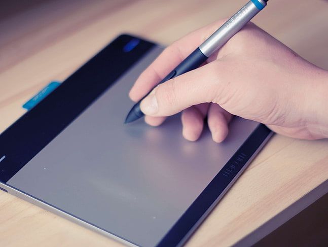A person using an external trackpad with a stylus in their hand.