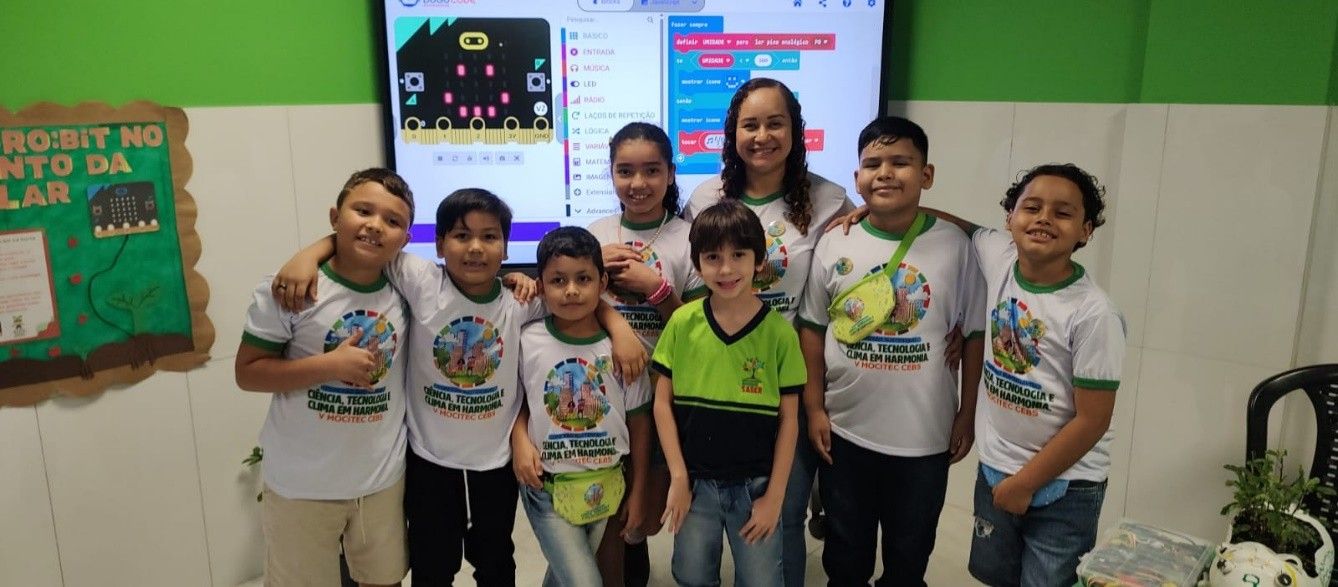 Students pose in front of a screen the presenting the code used in their project.