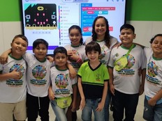 Students pose in front of a screen the presenting the code used in their project.