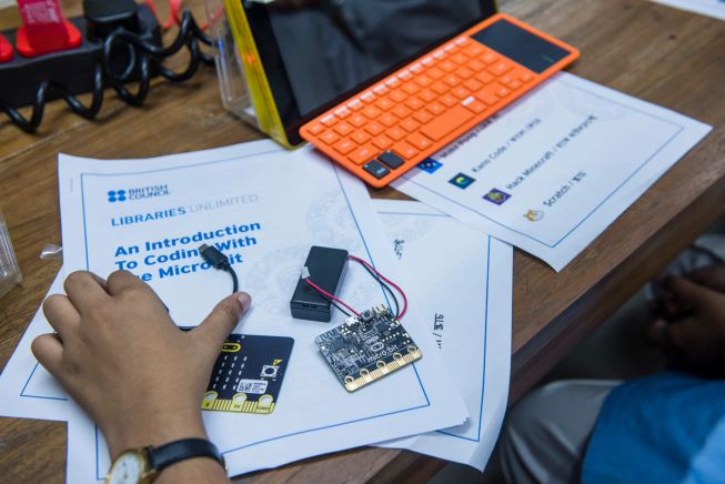 A students hands at desk with micro:bits and laptop