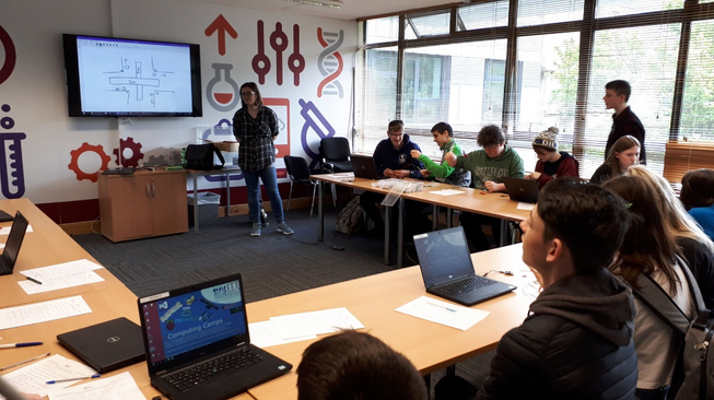 A teacher standing in front of a computing class