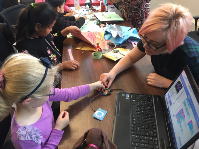 A teacher working with micro:bits with two young students