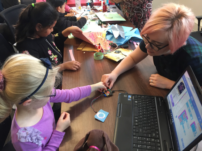 A teacher working with micro:bits with two young students