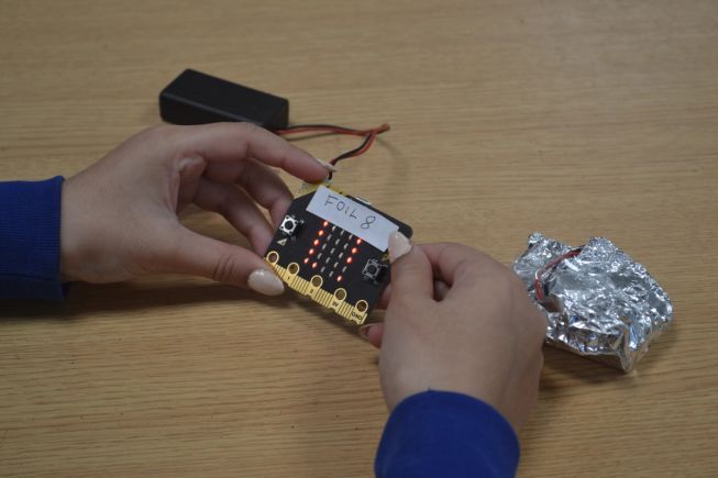 A student holds a micro:bit, linked to a micro:bit covered in foil, to test thermal insulation. Image: White Rose Science
