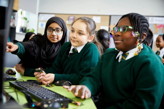Image of 3 female primary pupils using micro:bits and a computer