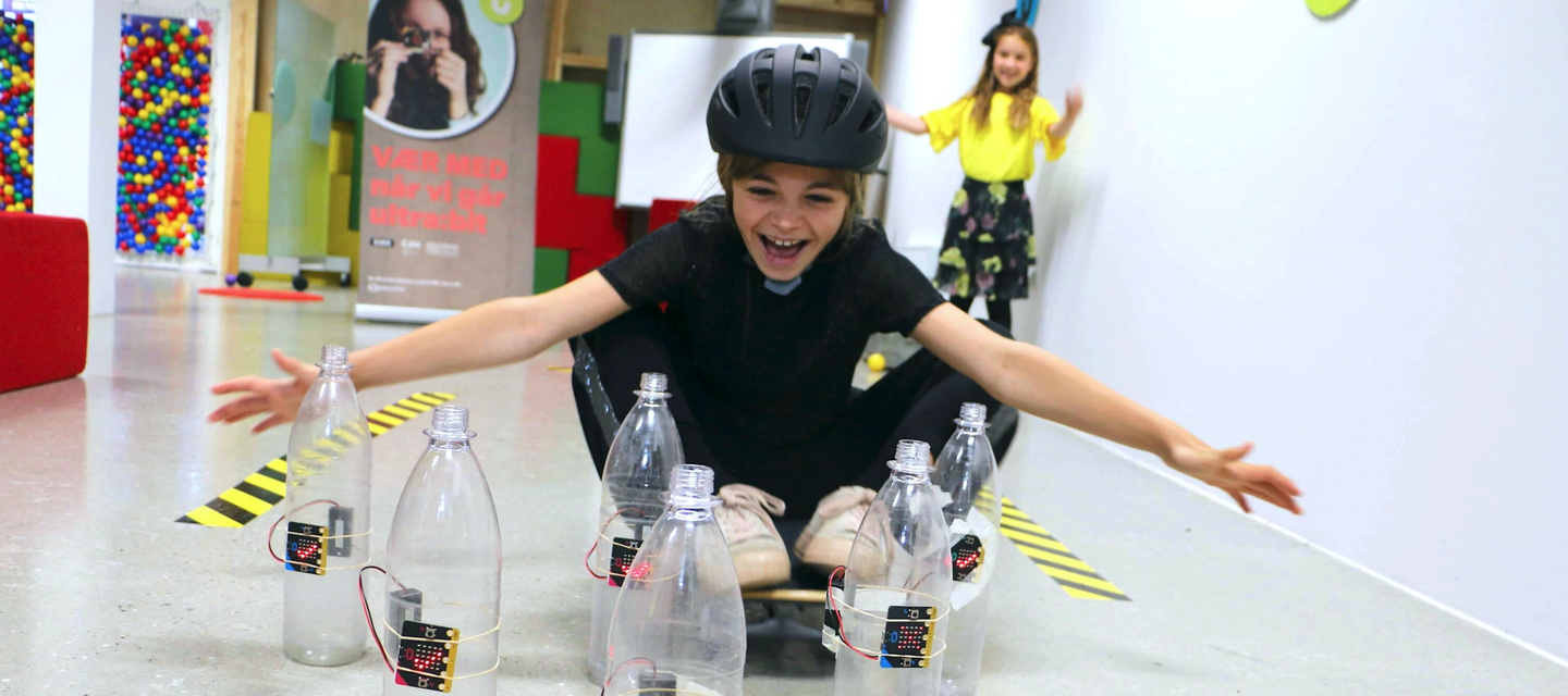 Girl playing skittles game with micro:bits inside plastic bottles