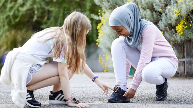 girl pointing at micro:bit step counter on another girl's shoe