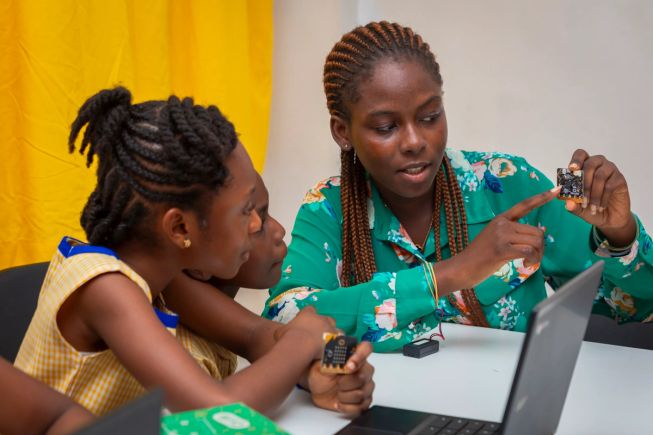 A teacher at a school in Ghana shows girls the back of the micro:bit