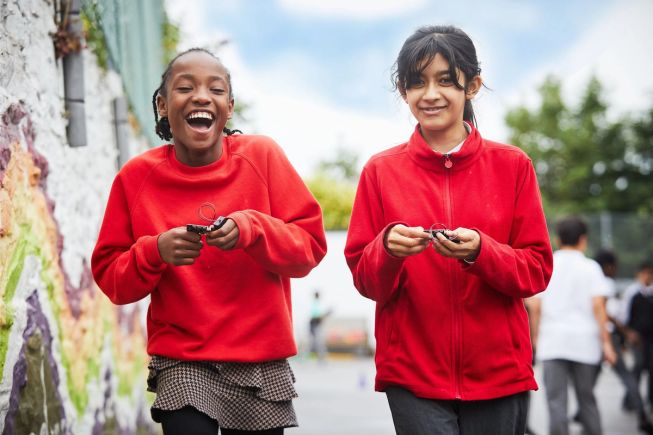 Two girls in red uniforms having fun in playground with micro:bits