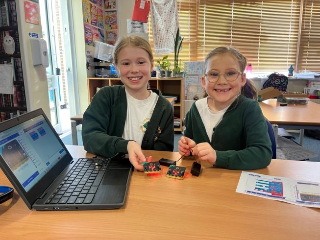 Two girls from Ivy Chimneys Primary School proudly show their coded micro:bits