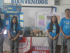 Students stand in front of a table with the alert system prototype and posters about their project.