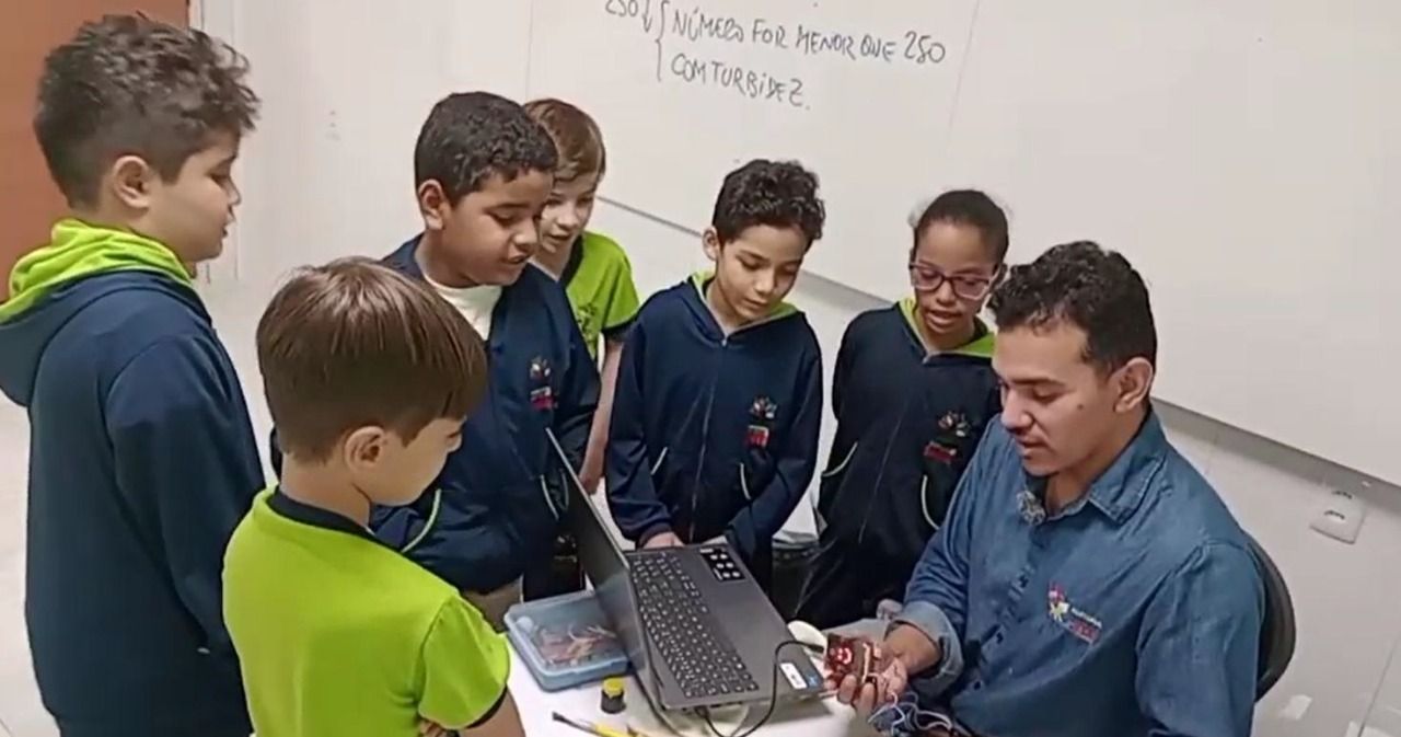 Students gather around their teacher while working on their water quality verification project with the micro:bit.