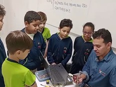 Students gather around their teacher while working on their water quality verification project with the micro:bit.