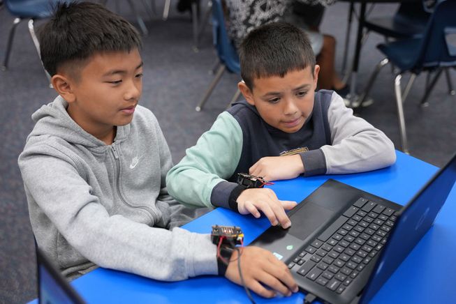 two pupils are coding the micro:bit together on a laptop