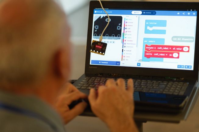 A teacher codes the micro:bit - their screen shows the code in Catalan