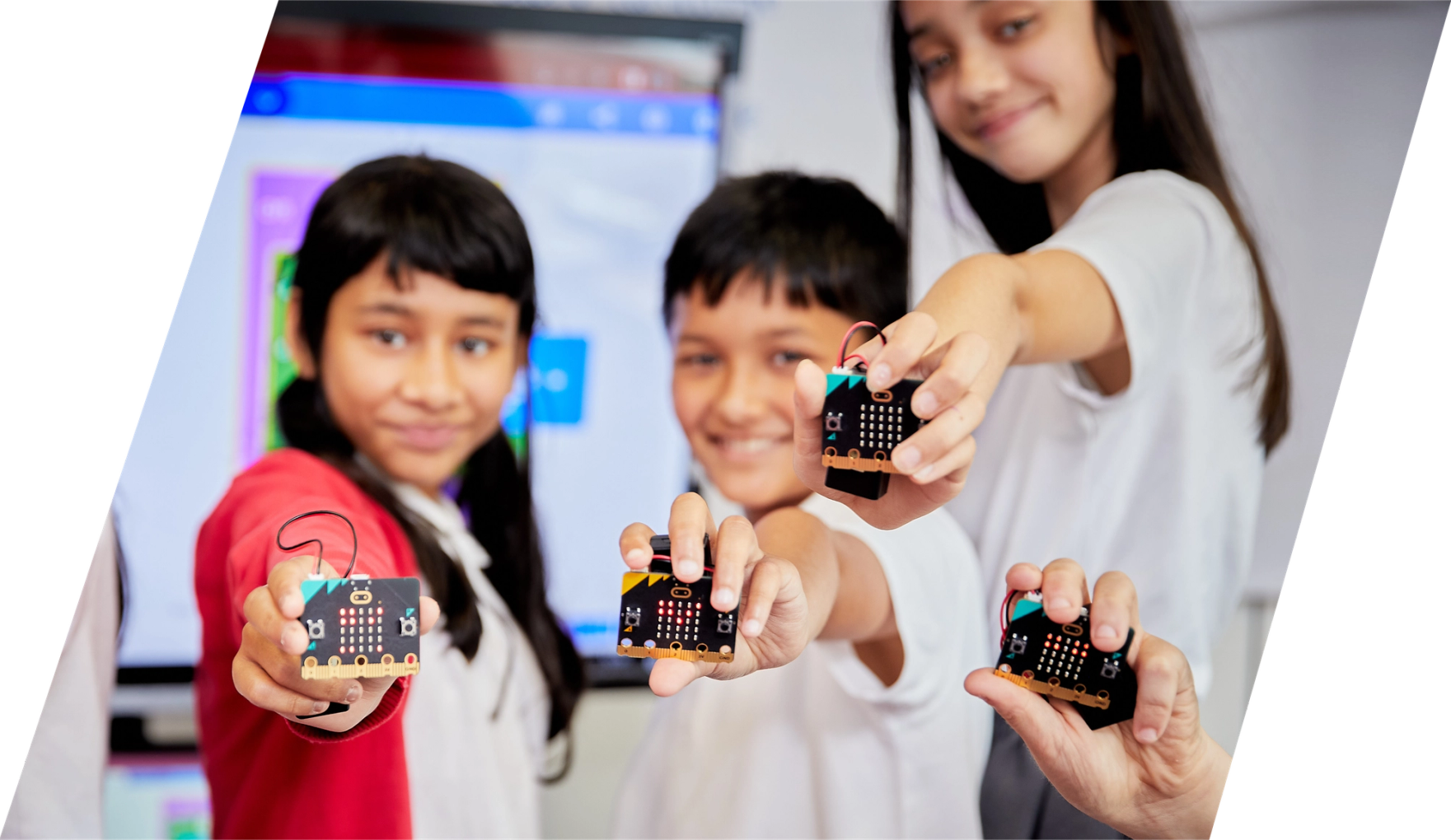 niños  en clase sonriendo  y sosteniendo micro:bits 