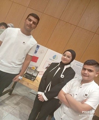 Students stand next to a poster and prototype of their project.