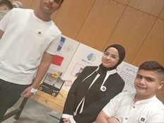 Students stand next to a poster and prototype of their project.