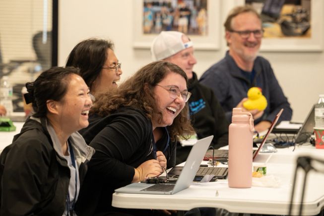 In the foreground, two female participants at micro:bit Live California laugh as they participate in a session