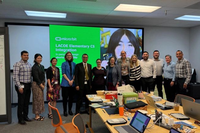 Education partners and micro:bit colleagues standing together in front of a screen displaying “LACOE Elementary CS Integration” during a workshop session.
