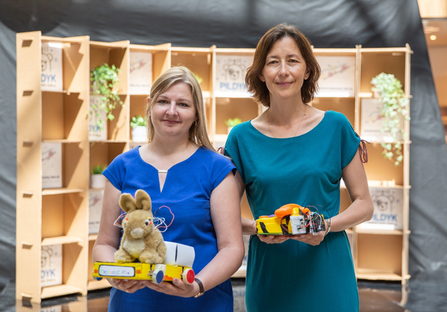 Two women standing together holding robot toys