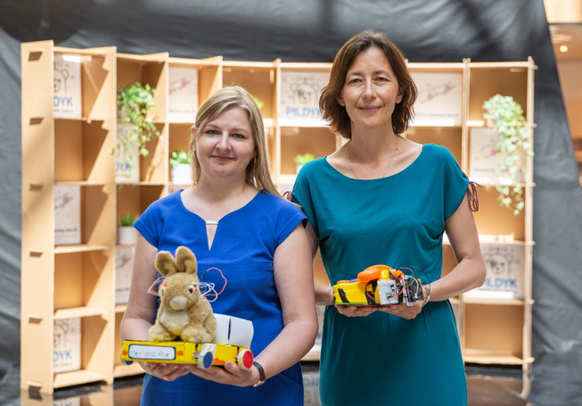 Two women standing together holding robot toys