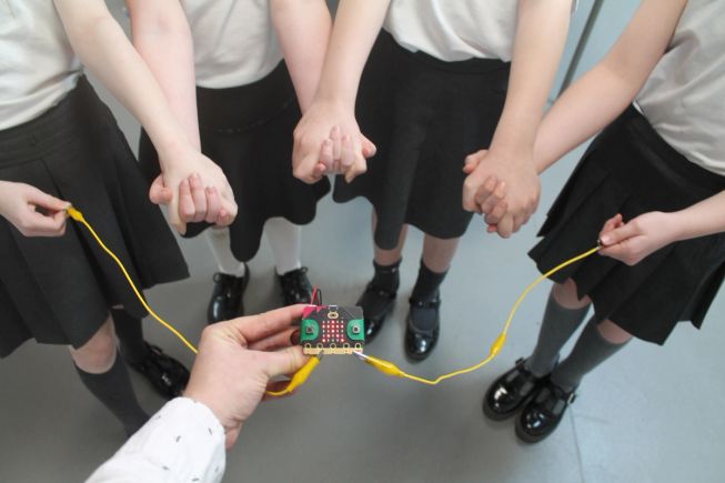 Four students holding hands, connected to a micro:bit, to make a human electrical circuit. Image: White Rose Science