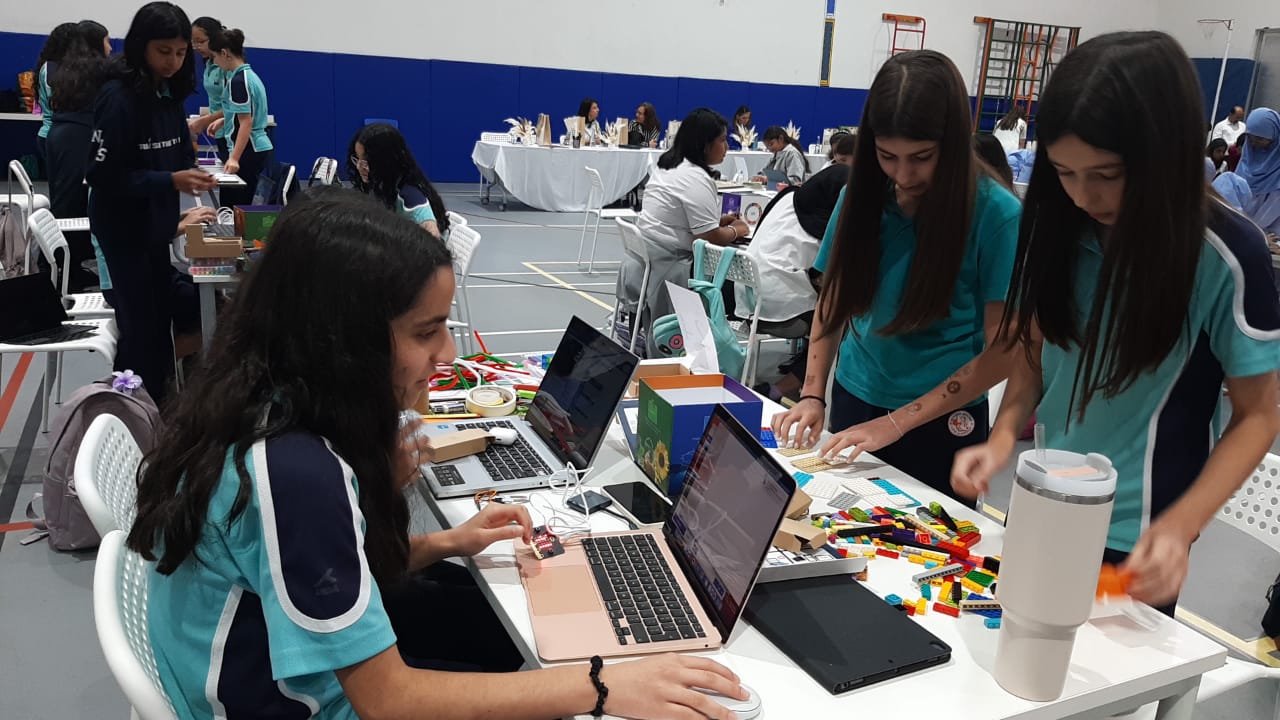 Students sit in front of laptops and their prototype of the soil moisture detector.