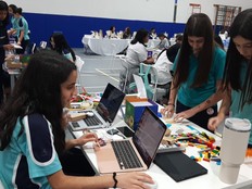 Students sit in front of laptops and their prototype of the soil moisture detector.
