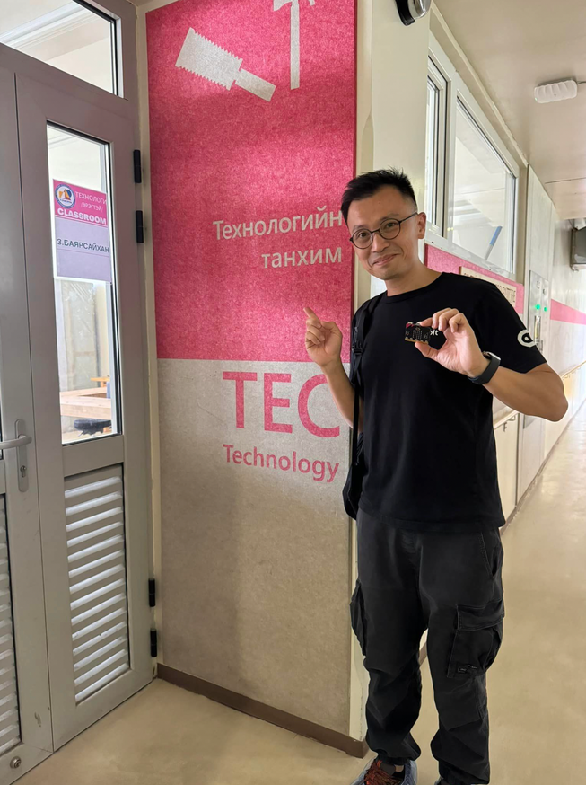 Head of APAC, Waris Candra, holding a micro:bit outside a school classroom in Mongolia