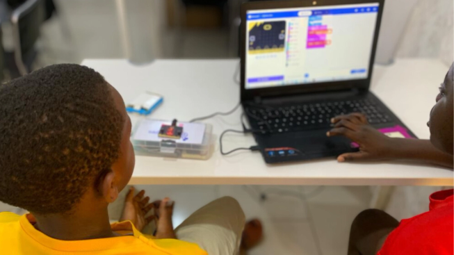 Looking over the shoulders of two children coding on a laptop with micro:bits