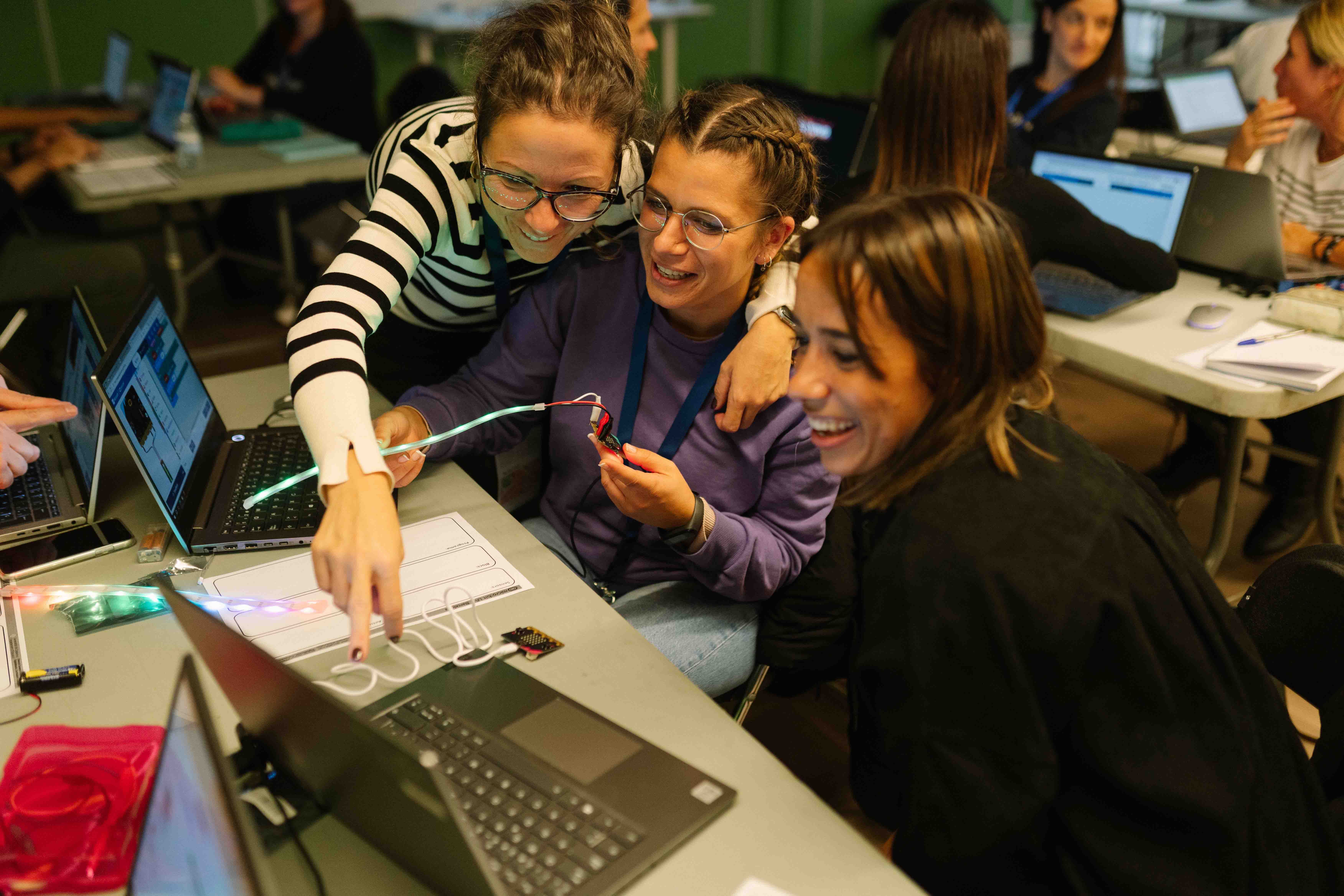 Three attendees to an event are playing with the micro:bit, enjoying the process of learning