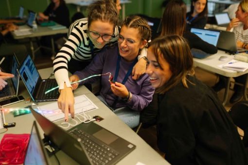 Three attendees to an event are playing with the micro:bit, enjoying the process of learning