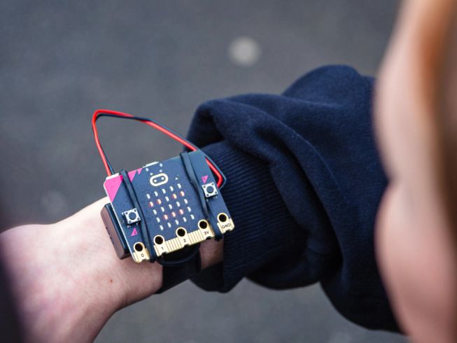 A micro:bit is attached to a child's wrist with the micro:bit wearable