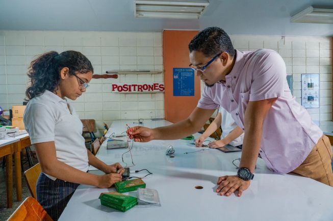 A teacher instructing a pupil on how to use a micro:bit