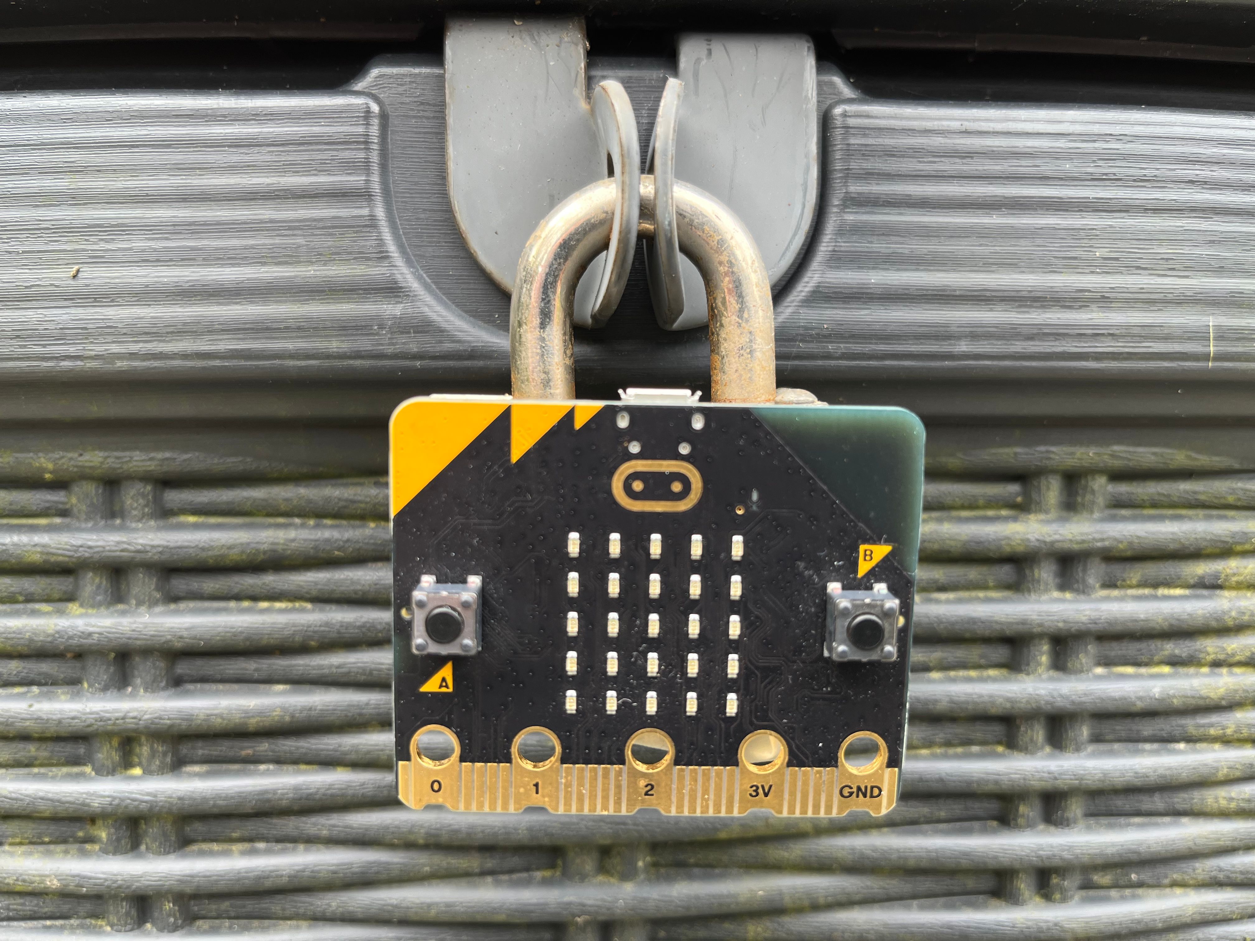 a micro:bit attached to a padlock securing a box