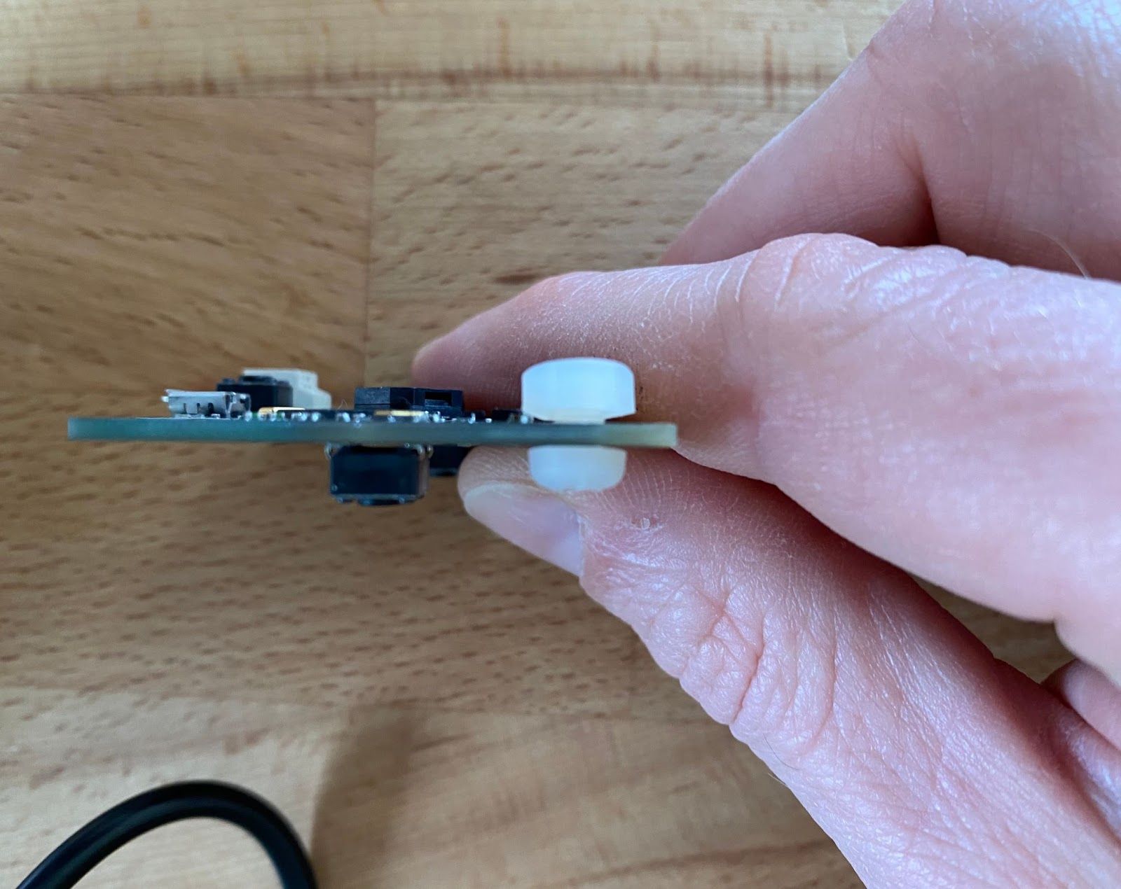 A side view of a micro:bit with nylon bolts through a pin hole. A small gap remains to allow wire to be hooked round the bolt before tightening.