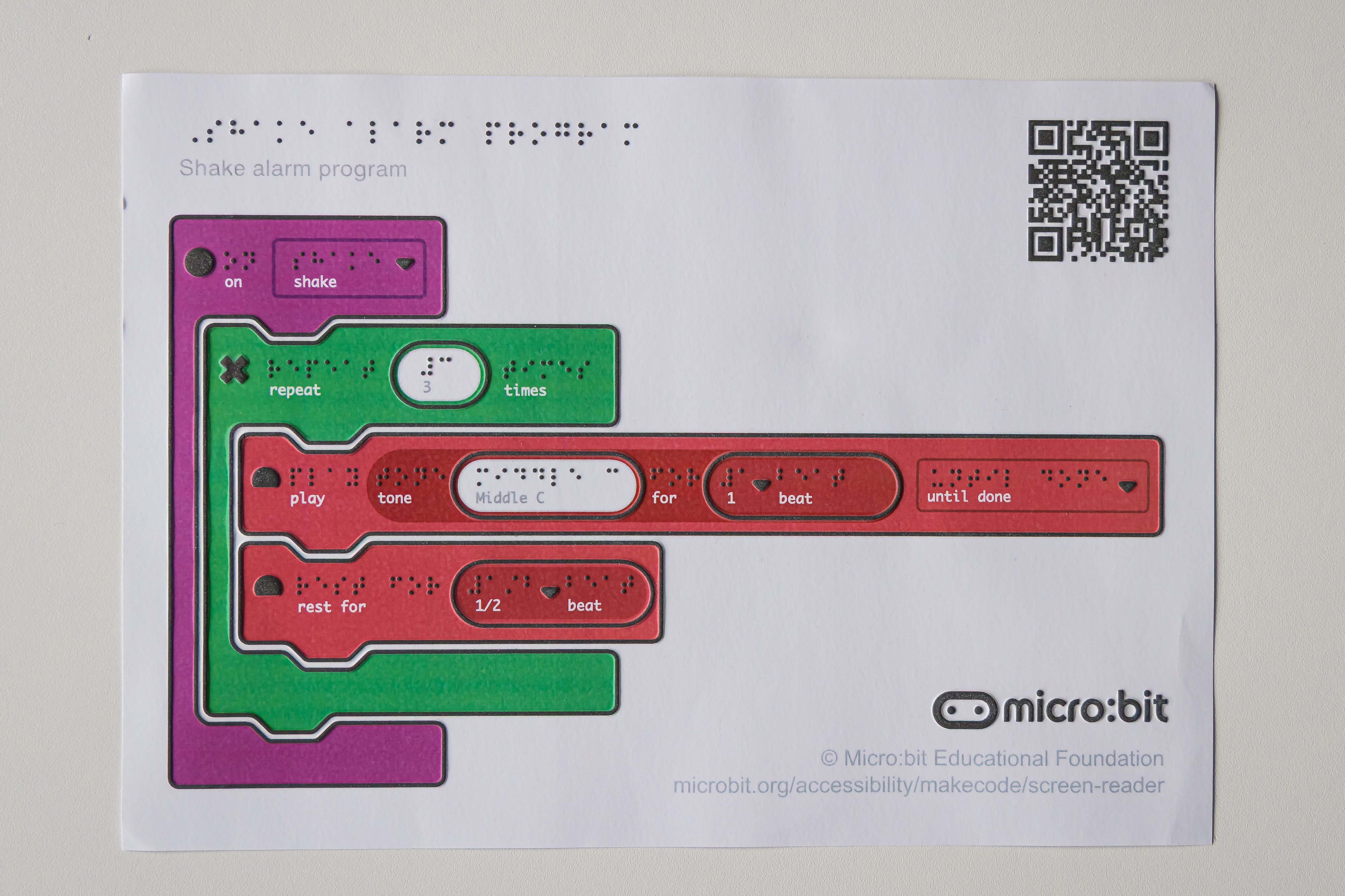 A single page program for the MakeCode Shake alarm project printed using a tactile graphics machine. The code blocks have tactile icons and braille text.