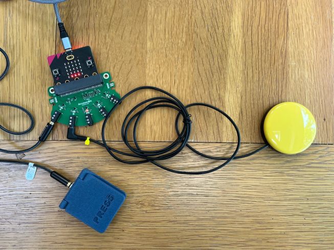 Prototype accessory for the micro:bit, with a square blue pressable switch, and a round yellow button