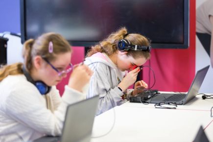 Two girls, each holding a micro:bit close to their eyes