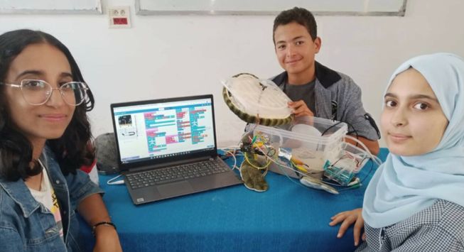 Three students with a tech invention and laptop