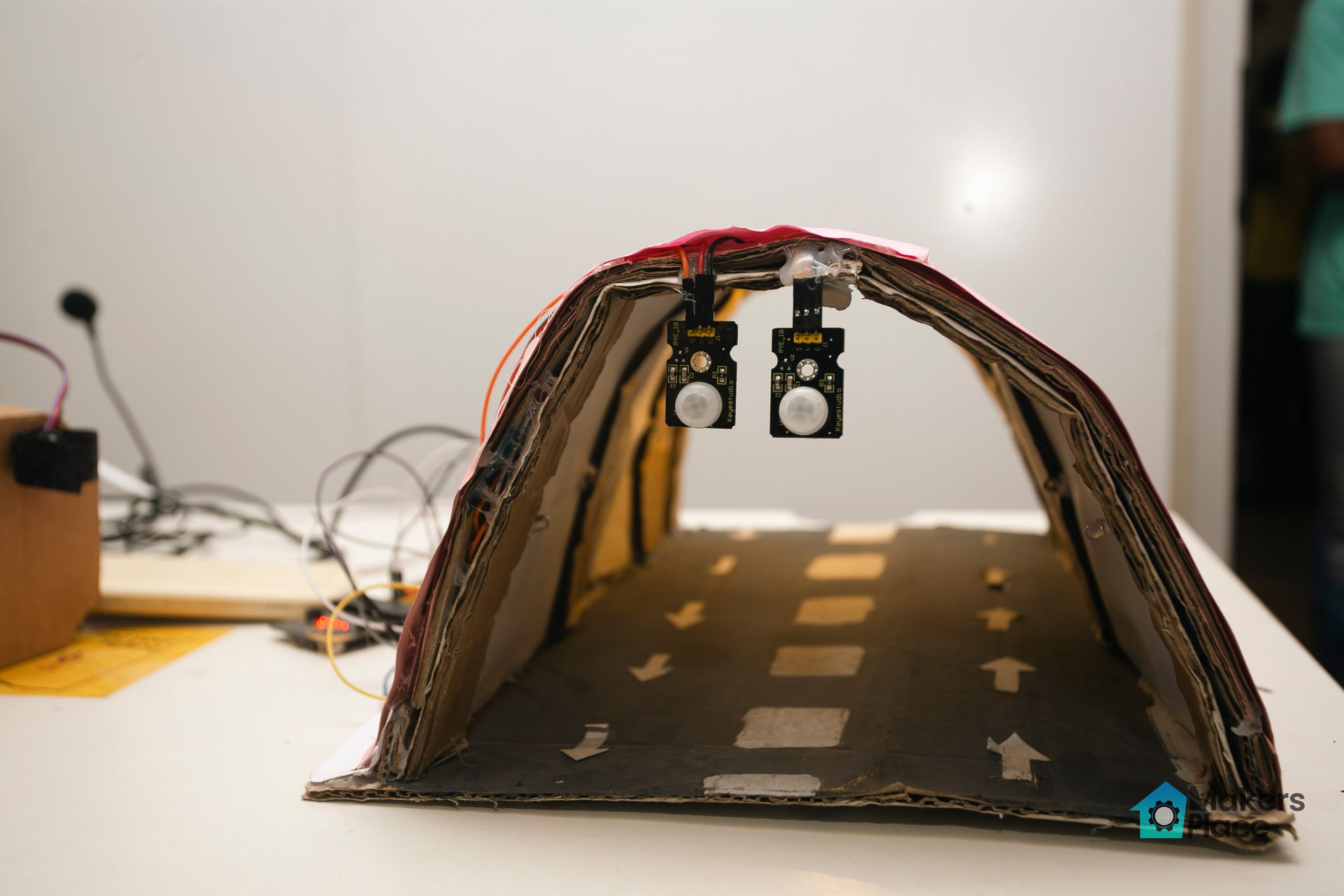 Close up photograph of the Smart Tunnel Lighting project showing two micro:bits suspended from the top of a cardboard tunnel.