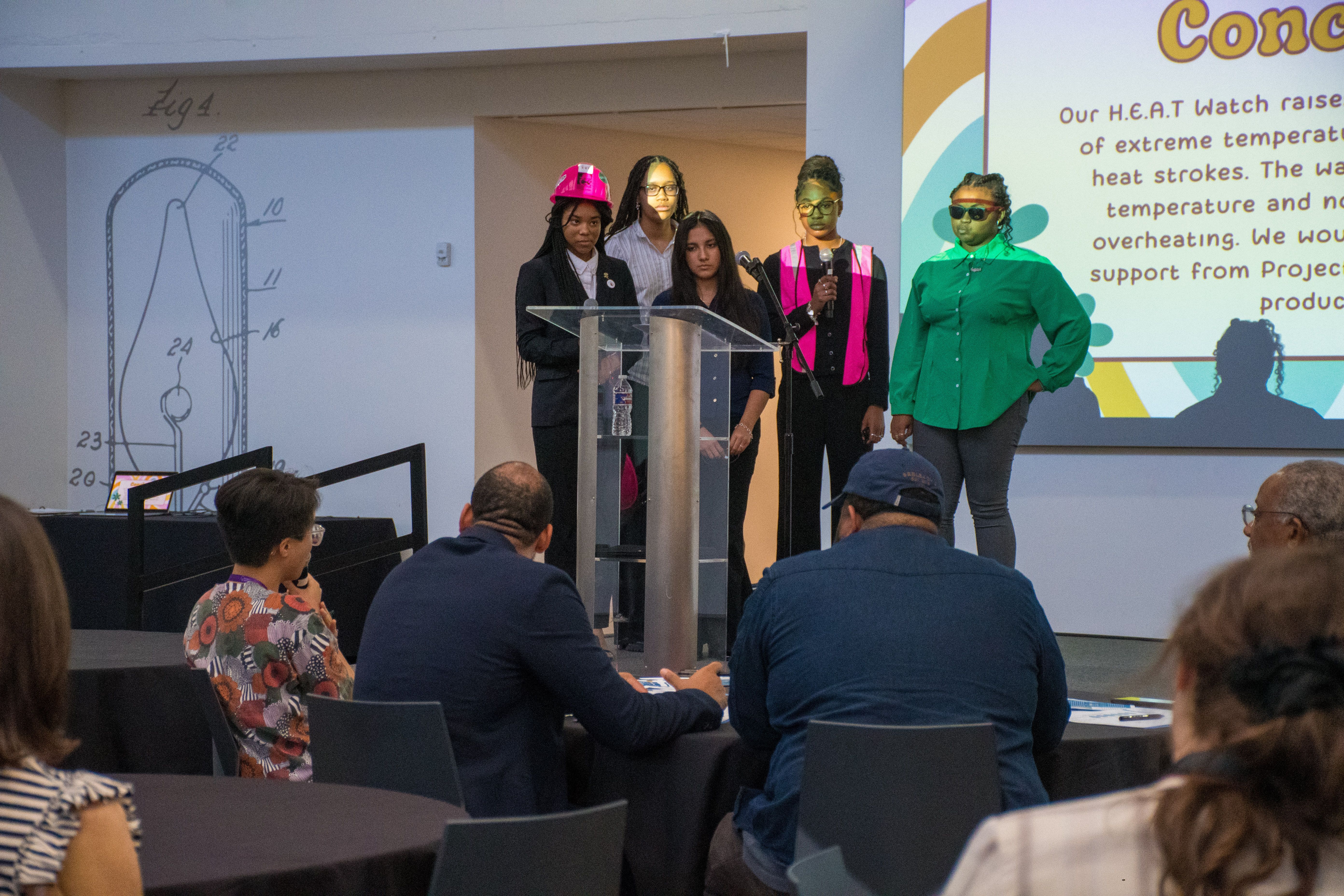 Students present the Tech 8 project behind a lectern.