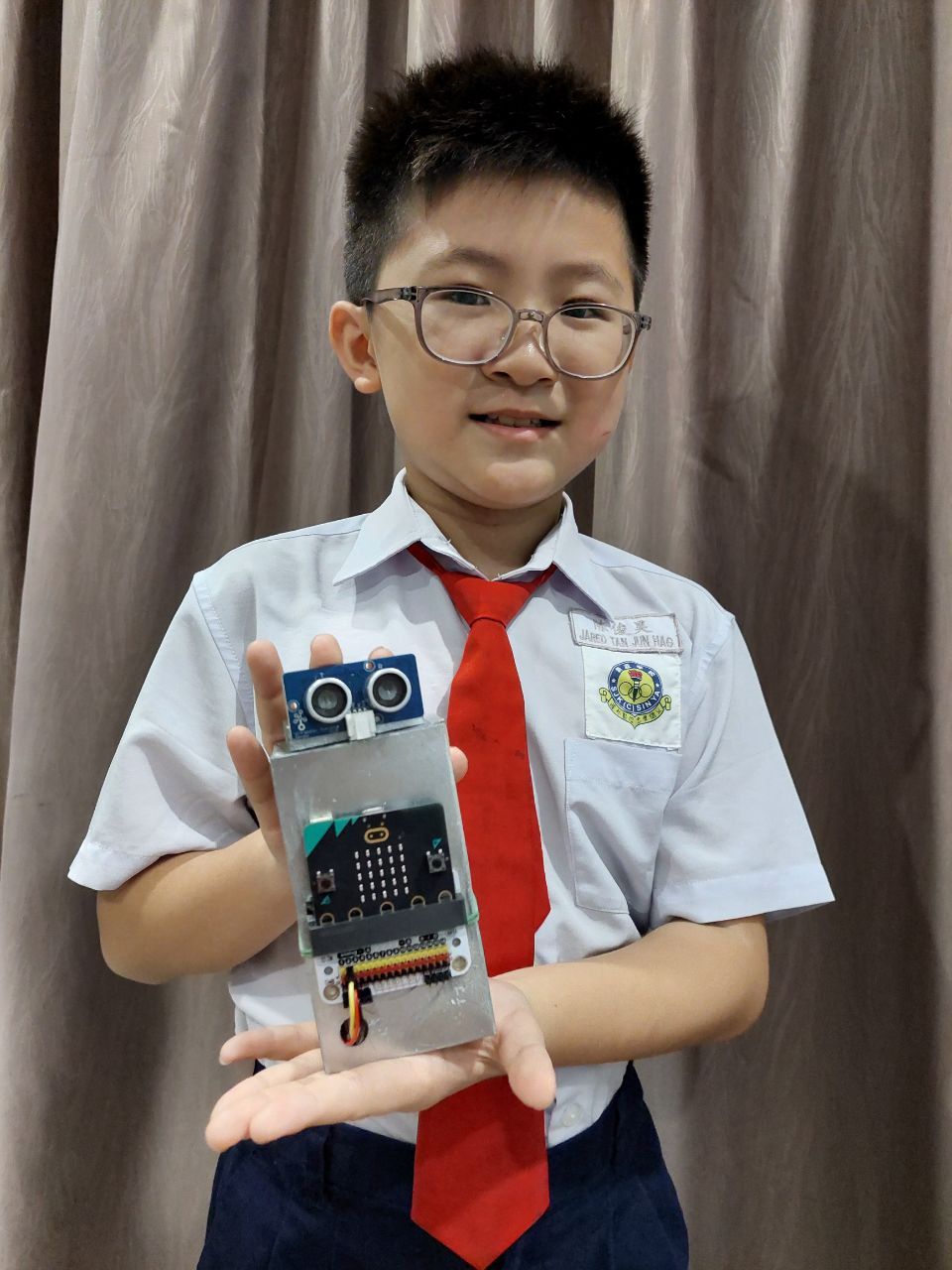 Jared holding his micro:bit creation. The 'E-mom' device. 