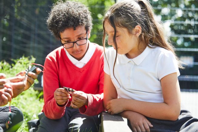 2 female pupils use a micro:bit outdoors